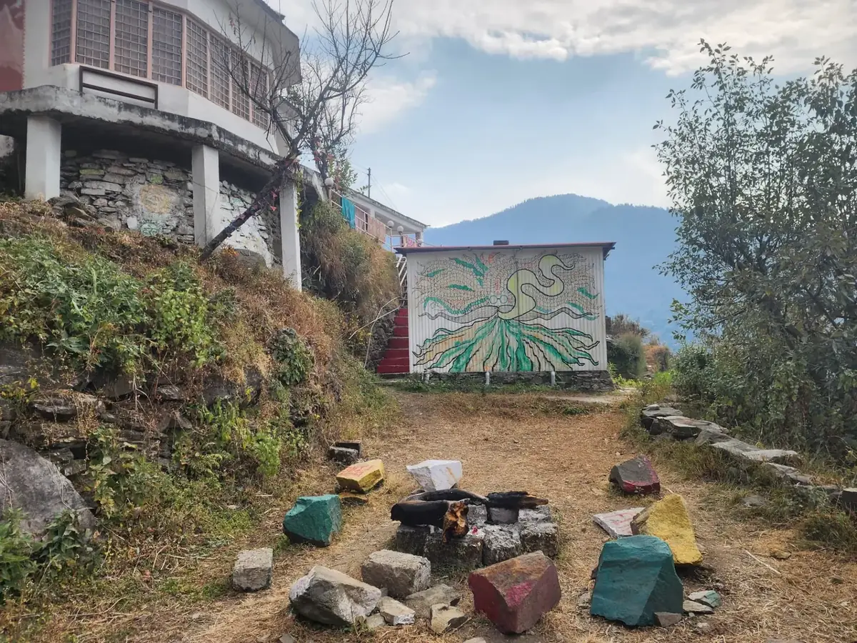 The bonfire area at The Aipan Retreat — painted stones and a fire circle in the open ground below the guest house