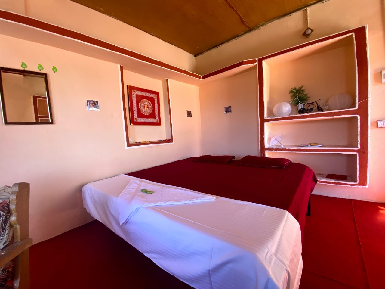 Triple-sharing room with two beds, warm clay walls, built-in niches and a framed wall hanging
