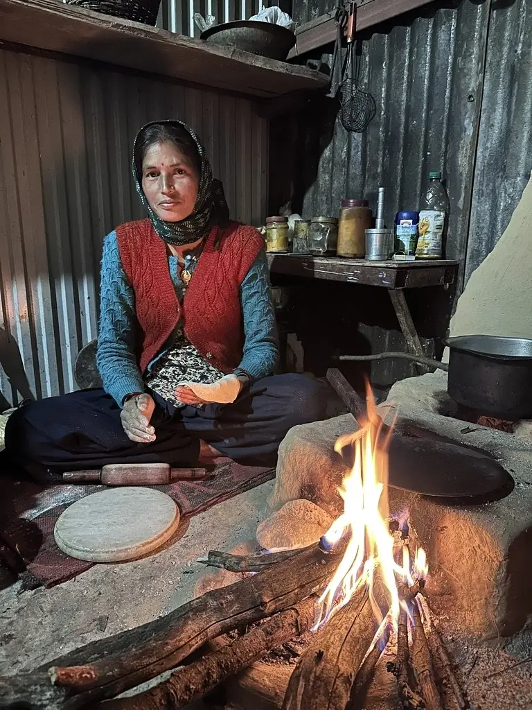 A woman making roti over an open fire in the retreat's rustic mountain kitchen