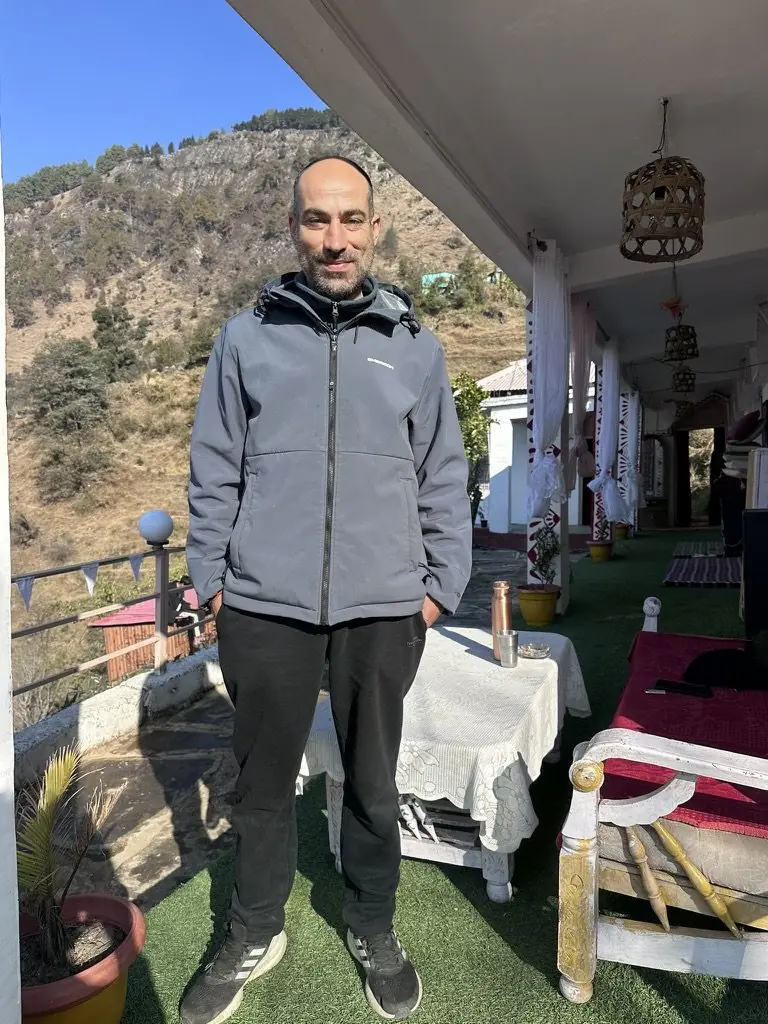 a guest standing on the terrace with Aipan-painted doorframes behind him