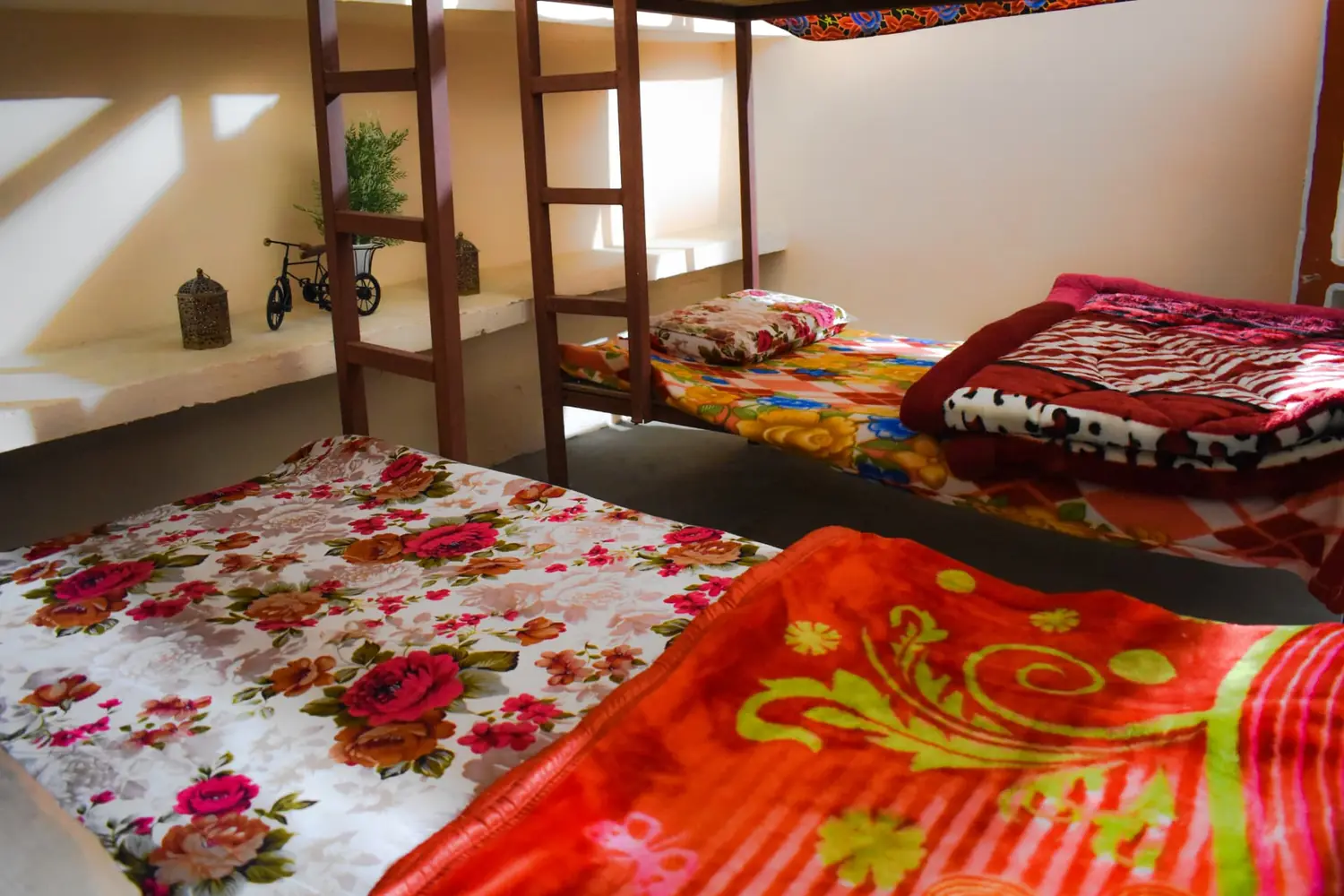 Bunk room interior with multiple beds, colourful blankets and wooden ladders