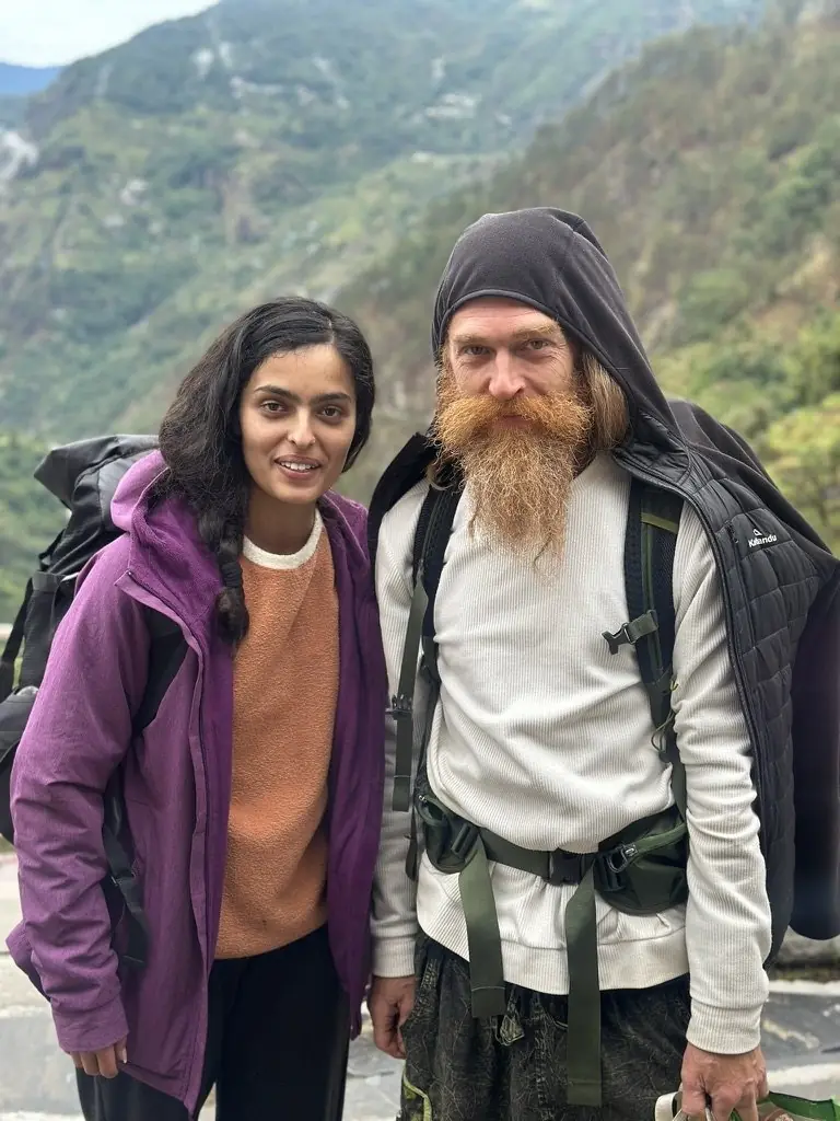 two travellers with packs paused on a mountain road