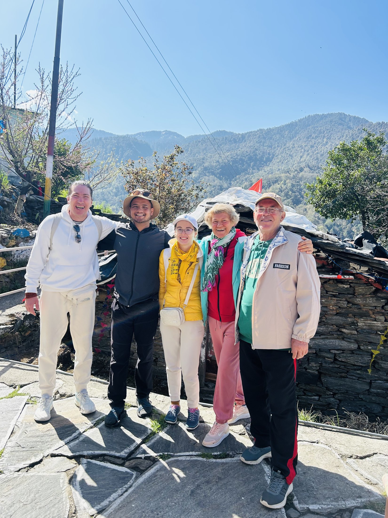 A group of happy guests with Adi, Kajal, and the Himalayan ridges behind them